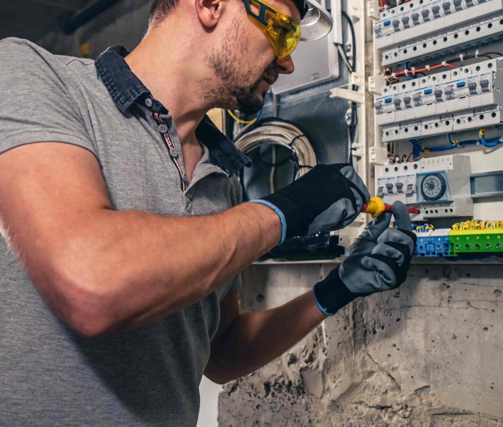 man-electrical-technician-working-switchboard-with-fuses-min